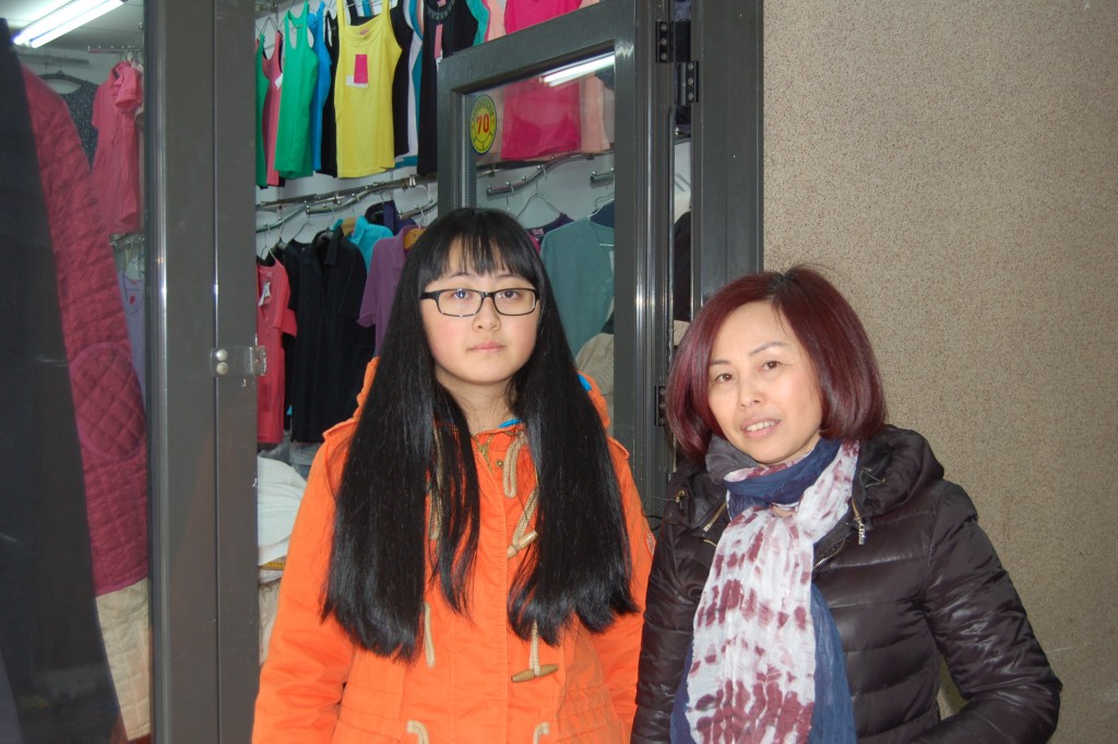 Zirui Yu et sa mère, devant l'enseigne familiale. La jeune adolescente veut construire sa vie à Belgrade.